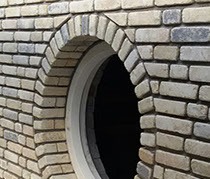 Rond venster met gemetselde boog in lichte steen