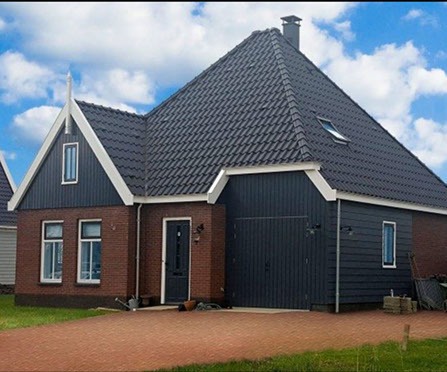 Woning met rode gevel en donkere houten schuurdeur